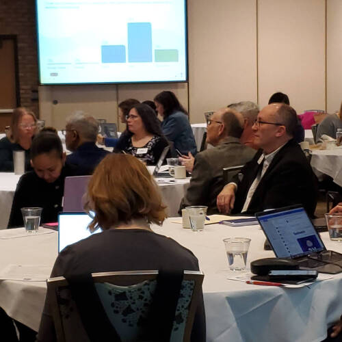 Attendees seated around a table at the GVSU Assessment Conference 2025, listening to keynote